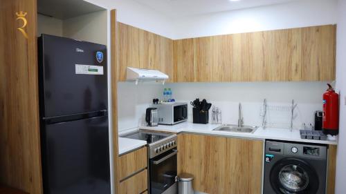 a small kitchen with a black refrigerator and a dishwasher at Luxury 2BR Duplex Oasis in Masdar City - Stylish Retreat Near Masdar Park & City Centre in Abu Dhabi