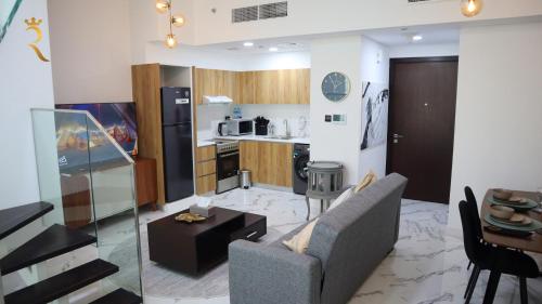 a living room with a couch and a kitchen at Luxury 2BR Duplex Oasis in Masdar City - Stylish Retreat Near Masdar Park & City Centre in Abu Dhabi