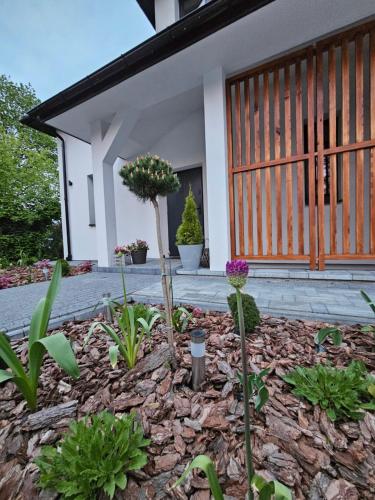 een tuin voor een huis met bloemen bij Pokoje przy Parkowej in Zwierzyniec
