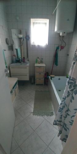 uma casa de banho com uma banheira, um lavatório e uma janela em Mitra Vendégház em Balatonalmádi