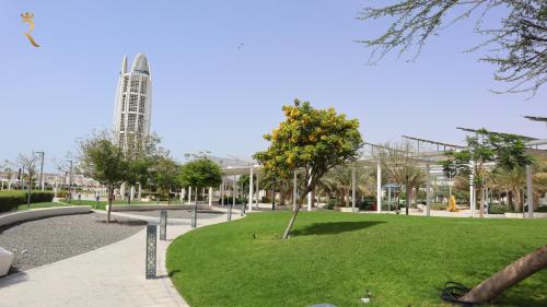 a park with a tree and a building in the background at Luxury 2BR Duplex Oasis in Masdar City - Stylish Retreat Near Masdar Park & City Centre in Abu Dhabi