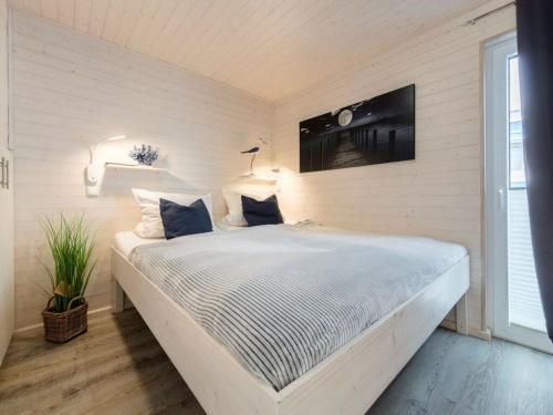 a bedroom with a large white bed with blue pillows at Houseboat Isa-Bella in Burgtiefe auf Fehmarn 