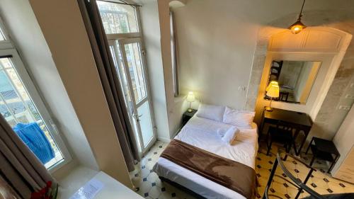 a bedroom with a bed and a desk and two windows at מלון בירת החומות• The Walled Capital Hotel in Jerusalem