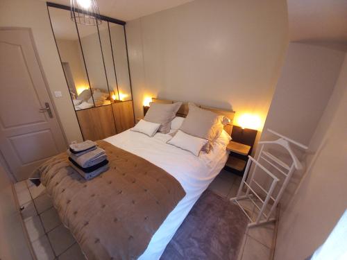 ein Schlafzimmer mit einem großen Bett mit weißer Bettwäsche und Kissen in der Unterkunft Appartement cosy au cœur du centre ville in Bourges