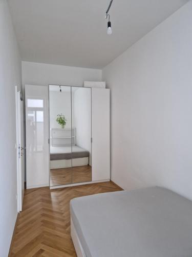 ein weißes Schlafzimmer mit einem Bett und einem Spiegel in der Unterkunft One-Bedroom Apartment with Garden in Wien