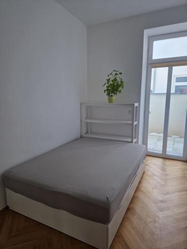 ein Bett in einem weißen Zimmer mit einer Pflanze darauf in der Unterkunft One-Bedroom Apartment with Garden in Wien