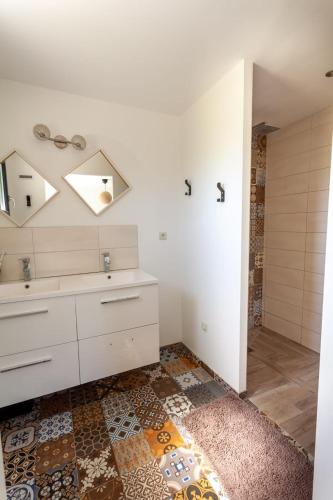 une salle de bain avec un lavabo et un miroir dans l'établissement maison de famille en pleine nature, à La Touche