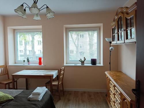 Habitación con mesa, mesa de comedor y 2 ventanas. en Apartament Kopernika, en Gdynia