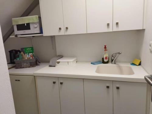 a kitchen with white cabinets and a sink and a microwave at Cozy apartment near to the airport in Kouvarás