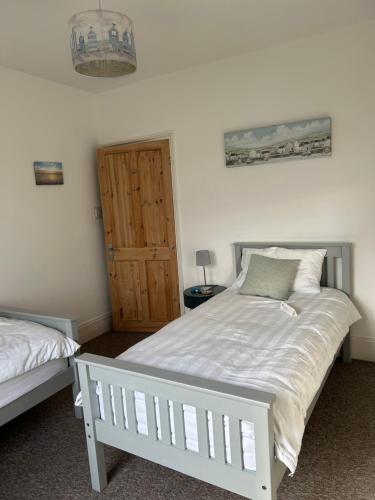 a bedroom with a white bed and a wooden door at Beresford81 in Cowes