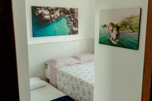 a bedroom with a bed and two pictures on the wall at Residencial Diva in Florianópolis