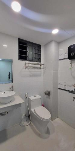 ein weißes Bad mit einem WC und einem Waschbecken in der Unterkunft Homestay in Sài Gòn in Ho-Chi-Minh-Stadt