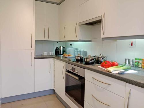 a kitchen with white cabinets and vegetables on the counter at Monmouth Aylesbury Retreat in Buckinghamshire