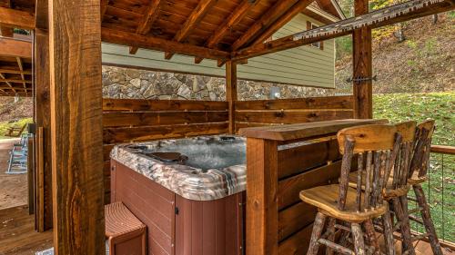 an outdoor hot tub in a wooden cabin with a chair at Meadow Creek Retreat in Cherry Log