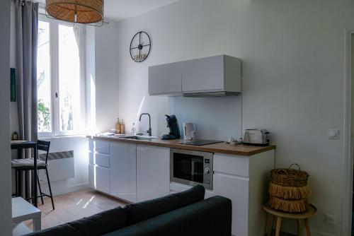 une cuisine avec des armoires blanches et un comptoir dans l'établissement Le Bazacle - Sublime Logement en Hypercentre, à Toulouse