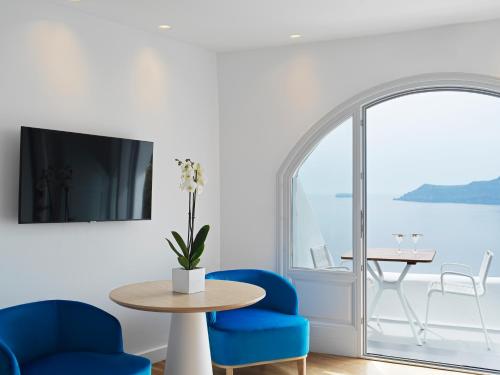 a dining room with blue chairs and a table and a window at Katikies Santorini - The Leading Hotels Of The World in Oia