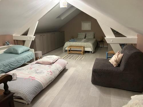 Cette chambre mansardée comprend deux lits et un canapé. dans l'établissement Charmante petite maison en pierre, à Boutigny-sur-Essonnes