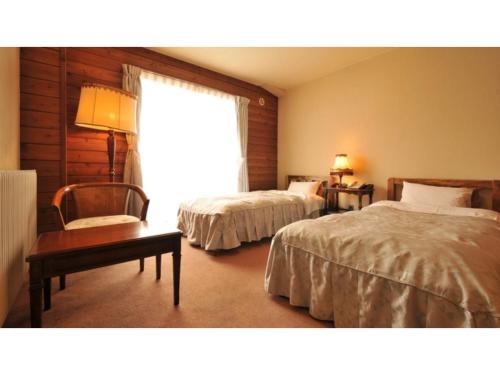 a bedroom with two beds and a chair and a window at Hotel Takimoto - Vacation STAY 43487v in Yamanouchi