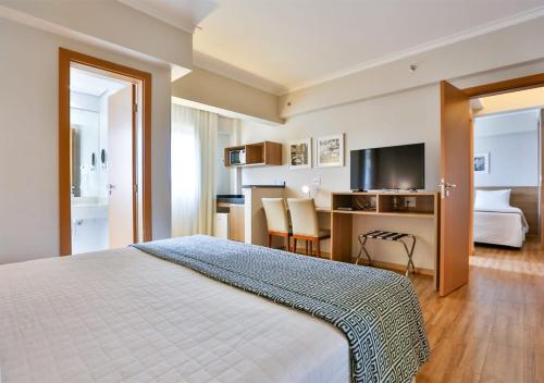 um quarto de hotel com uma cama e uma secretária em Matiz Vilaboim Ribeirão Preto em Ribeirão Preto