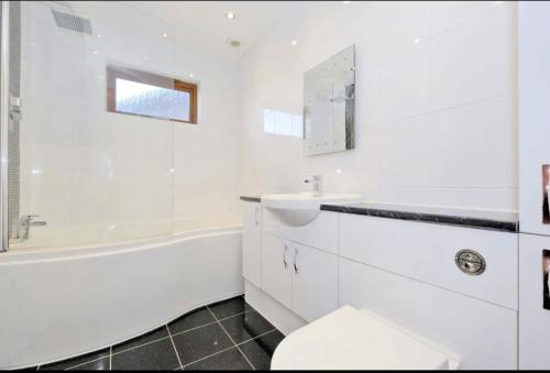 La salle de bains blanche est pourvue d'un lavabo, d'une baignoire et de toilettes. dans l'établissement Sunny Cove Holiday Let, à Aberdeen