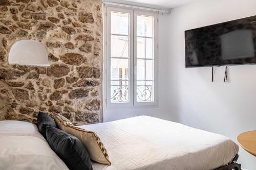 a bedroom with two beds and a stone wall at Cozy renovated 1 bedroom Suquet Cannes Center - 1BR in Cannes