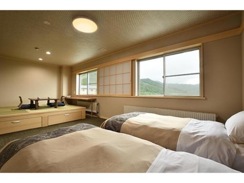 two beds in a room with a window at Hotel Takimoto - Vacation STAY 43490v in Yamanouchi