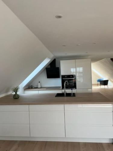 a kitchen with white cabinets and a staircase at Lækker lejlighed på havnefronten in Nakskov