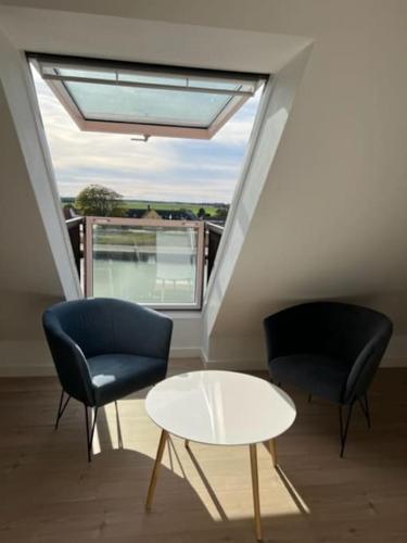 two chairs and a table in a room with a window at Lækker lejlighed på havnefronten in Nakskov