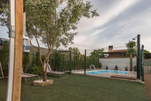 a fence with a tree and a swimming pool at Almagrocasarural in Almagro