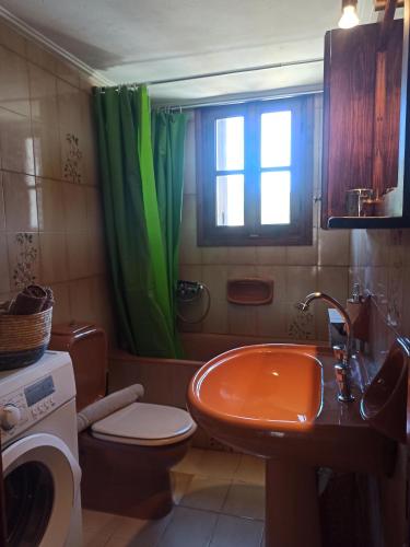 a bathroom with an orange sink and a green shower curtain at Seaside Selana Home in Nikiana