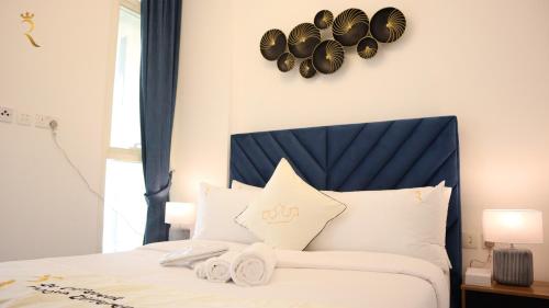 een slaapkamer met een wit bed met hoeden aan de muur bij Duplex 2BR Delight - Masdar City in Abu Dhabi