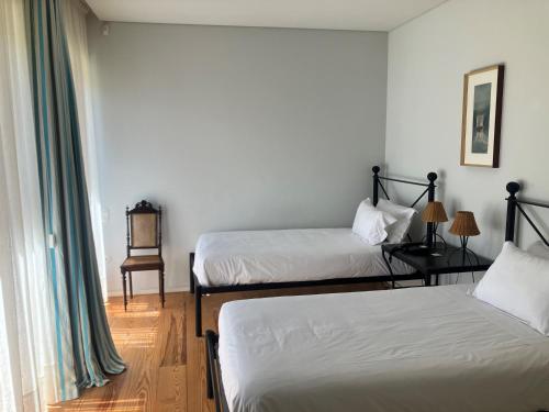 a room with two beds and a table with a chair at Quinta Dona Matilde in Peso da Régua