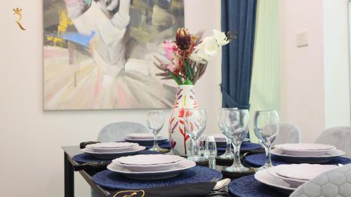 a table with plates and glasses and a vase with flowers at Stylish 2BR Duplex - Chic Masdar Modern Stay in Abu Dhabi
