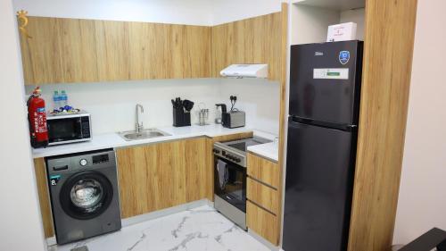 a small kitchen with a black refrigerator and a washing machine at Stylish 2BR Duplex - Chic Masdar Modern Stay in Abu Dhabi