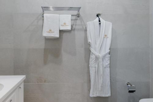 Tumar Hansa Ethno Hotel في أستانا: بدلة بيضاء معلقة على جدار في الحمام