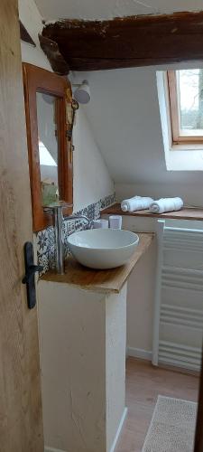 La salle de bains est pourvue d'un lavabo et d'un miroir sur un comptoir. dans l'établissement La chambre de la maison du four à pain, à Grandchamp
