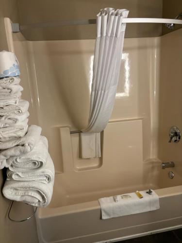 een badkamer met een douche en een stapel handdoeken bij Super 8 by Wyndham Escanaba in Escanaba