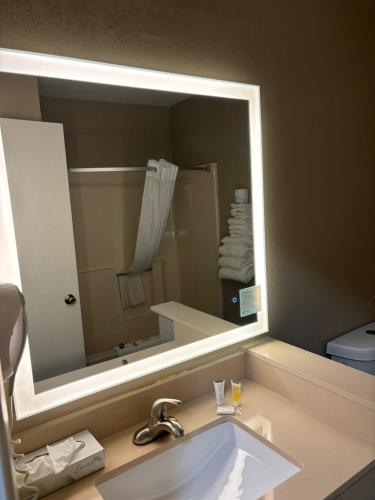 a bathroom with a large mirror over a sink at Super 8 by Wyndham Escanaba in Escanaba