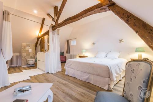 une chambre avec un grand lit blanc et une salle de bain dans l'établissement Au bord de l'étang - Le Presbytère, à Montaigu