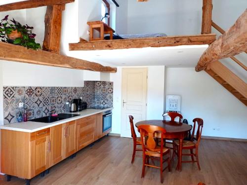 uma cozinha com armários de madeira e uma mesa e cadeiras em Studio de charme avec vue, en plein coeur de Florac em Florac