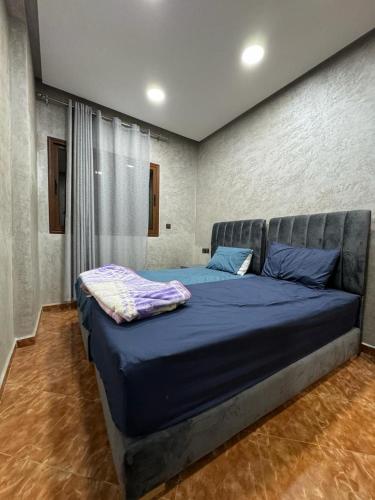 appartement spacieux في Deroua: غرفة نوم عليها سرير وملاءات زرقاء