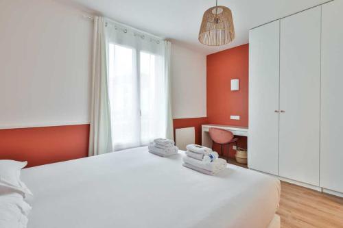 ein Schlafzimmer mit einem weißen Bett und Handtüchern darauf in der Unterkunft Super appartement 4P 1BR Marché aux Puces in Saint-Ouen