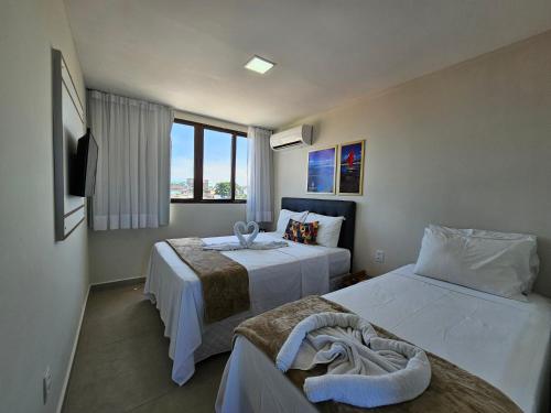 a hotel room with two beds and a window at Porto de Galinhas PORTO EXCLUSIVE BY AFT in Porto De Galinhas