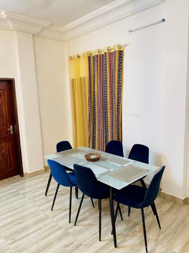 uma sala de jantar com uma mesa e cadeiras azuis em BEL APPARTEMENT CALME ET PAISIBLE em Cadjèhoun