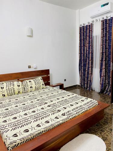 a bedroom with a bed with a black and white comforter at BEL APPARTEMENT CALME ET PAISIBLE in Cadjèhoun