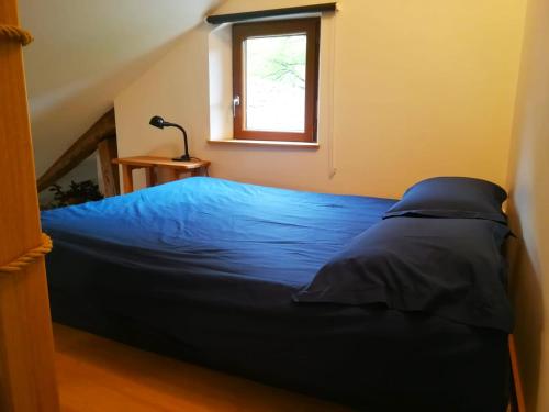 um quarto com uma cama azul e uma janela em Studio de charme avec vue, en plein coeur de Florac em Florac