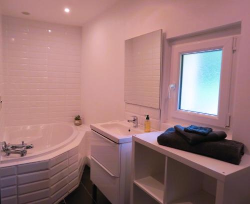 ein weißes Badezimmer mit einer Badewanne und einem Waschbecken in der Unterkunft Le Gîte du Coin - Maison de vacances avec jardin in Le Bocasse