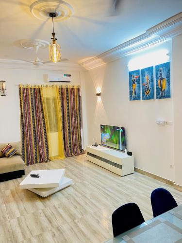 uma sala de estar com uma televisão de ecrã plano e um sofá em BEL APPARTEMENT CALME ET PAISIBLE em Cadjèhoun