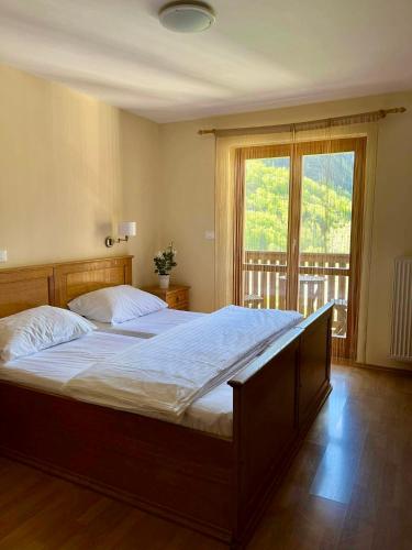 a bedroom with a large bed and a large window at Hotel Alpine in Log pod Mangartom