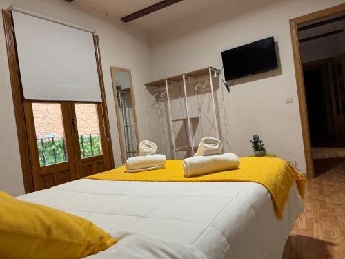 a bedroom with a yellow and white bed with two towels at La Sal Home Toledo in Toledo
